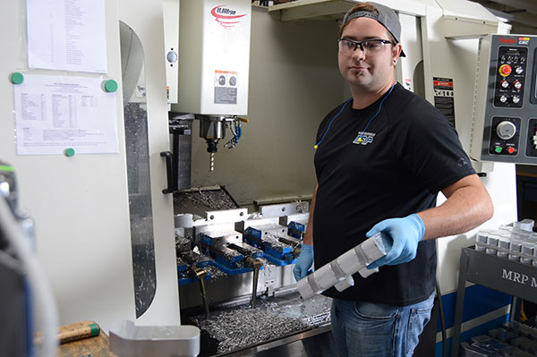 Man removing milled part from CNC machine